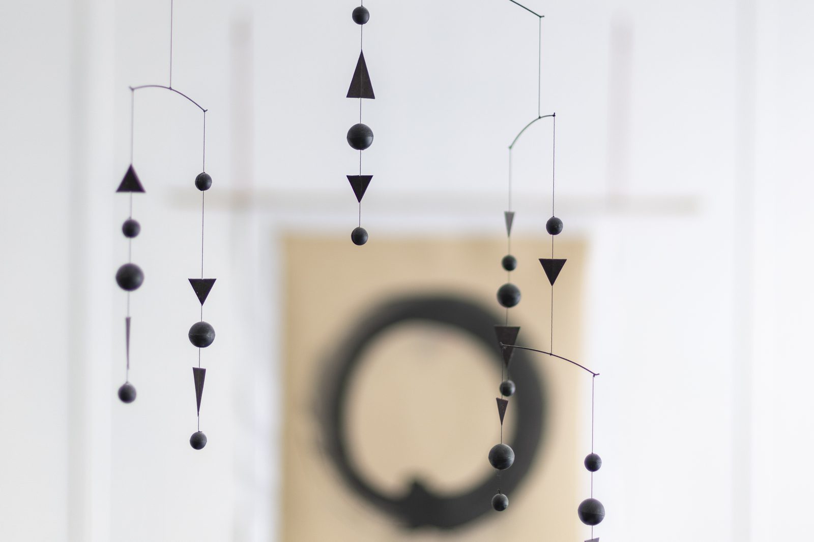 Mobile suspendu devant une calligraphie d’ensō
